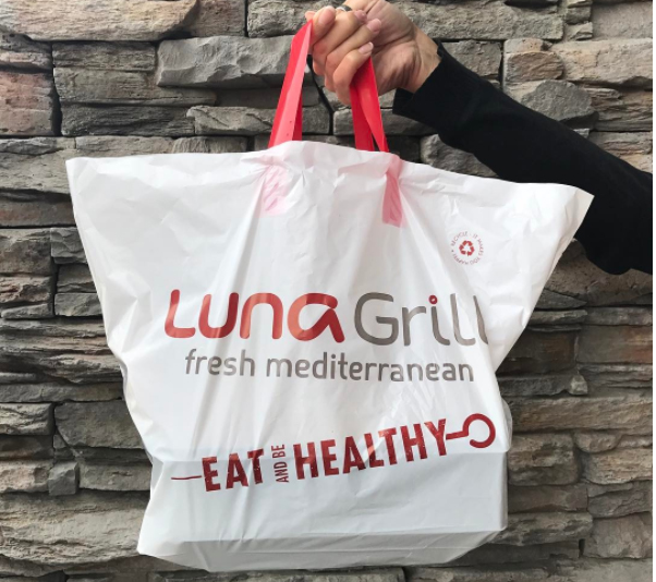 Hand holding a Luna Grill restaurant bag