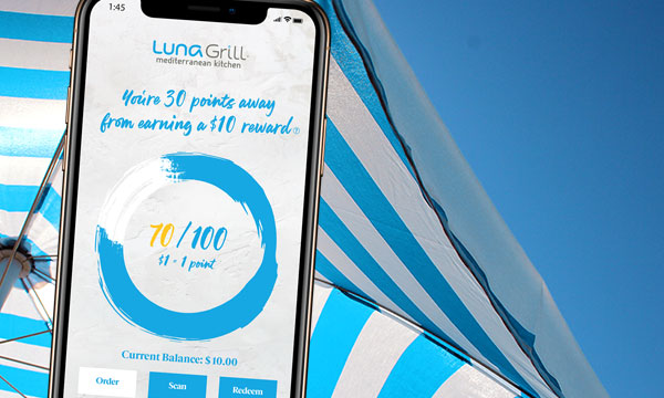 phone with luna grill rewards app over a blue sky and umbrella background
